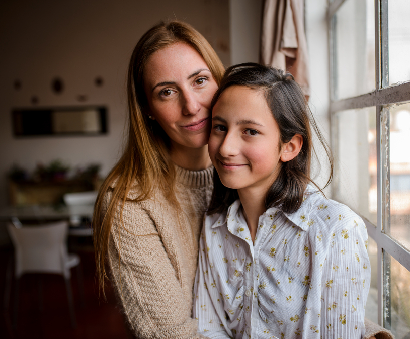 moeder en dochter staan bij een raam